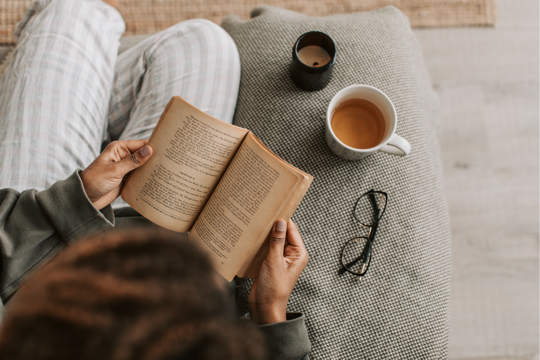 Person reading with coffee and glasses nearby